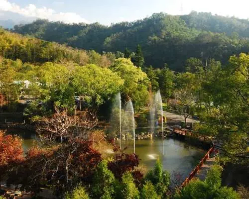 東勢林場湖光山色全景，湖中噴泉與四周紅綠黃相間的樹木，展現台中森林度假的豐富自然風貌。