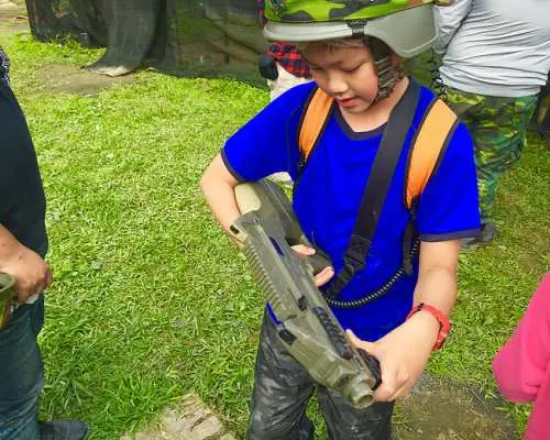 特寫一名戴著迷彩頭盔的孩童手持高科技鐳射槍，在台北準備參與一場無痛且安全的射擊體驗。