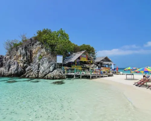 맑은 터키색 바다, 작은 물고기떼, 바위, 해변 오두막, 다채로운 파라솔이 있는 카이섬 해변. 스노클링과 휴식에 완벽한 장소입니다.