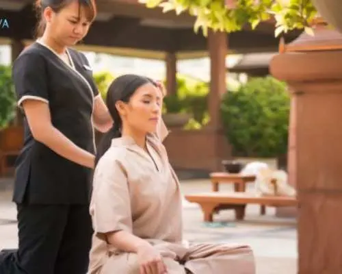 At Viva Jiva Spa's outdoor area in Bangkok, a client performs stretching and relaxation guided by a professional therapist, experiencing mind-body balance inspired by Eastern wisdom.