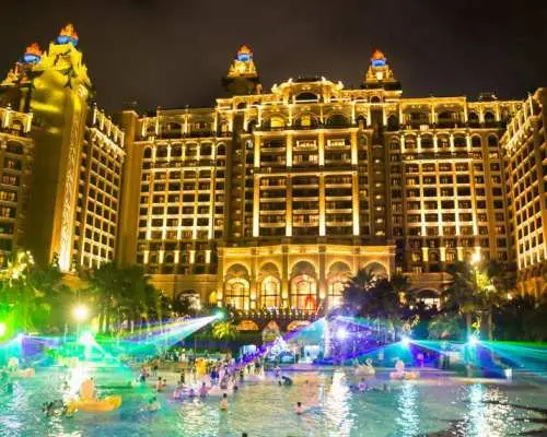 夜晚的長隆橫琴灣酒店，戶外水上樂園被繽紛燈光照亮，遊客在泳池中暢玩，享受熱鬧的夜間娛樂。