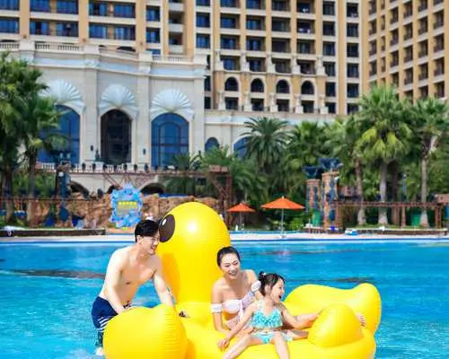 一家三口在珠海長隆橫琴灣水世界，興奮地乘坐巨型黃色小鴨造型充氣船，盡情享受泳池樂趣。