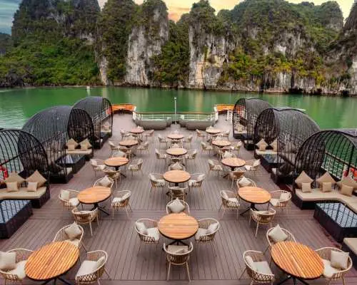 Ambassador luxury cruise's unique outdoor sundeck with stylish dome-shaped seating and tables, perfect for enjoying meals amidst Halong Bay's stunning scenery.