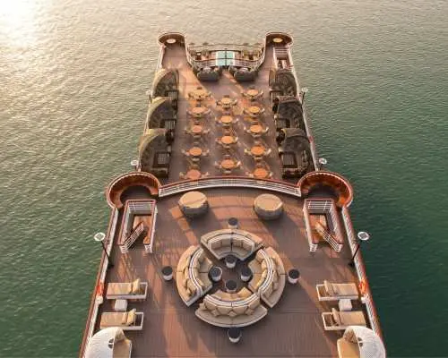 Spacious top deck of the Ambassador luxury cruise in Halong Bay, featuring comfortable lounge seating and relaxation areas perfect for enjoying sunset views.