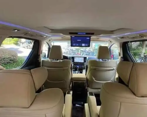 Spacious and luxurious interior of a Hong Kong airport transfer private car, featuring comfortable beige seats and an entertainment system, ensuring passengers enjoy a safe and convenient journey.