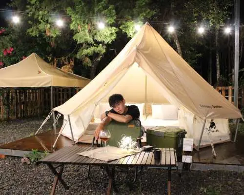 南投光隅免裝備露營體驗，遊客在鐘型帳篷前享受夜晚，戶外桌擺設飲品，體驗悠閒放鬆的露營樂趣。