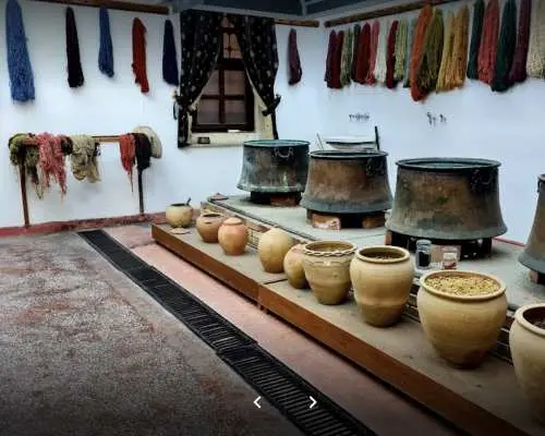 A traditional Cappadocia carpet dyeing workshop, featuring large pots and clay vessels for natural dyes, with colorful yarns hanging, illustrating the vibrant art of carpet making.