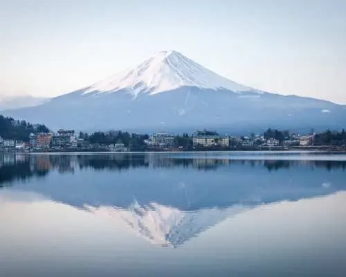 雄偉的富士山白雪皚皚，倒映在寧靜的湖水中，展現機場專車接送服務能便捷抵達富士山、箱根、伊豆等自然風光區。