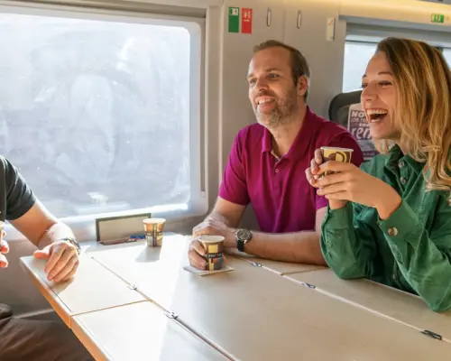 広々とした快適なスペイン高速列車内で飲み物を楽しむ旅行者たち。マドリードからトレドへの迅速で環境に優しい旅を体験しています。