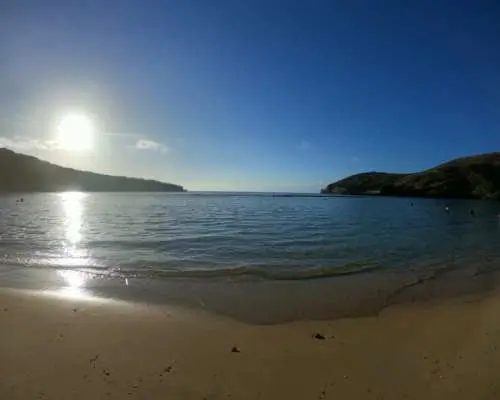 全米No.1に選ばれた美しいハナウマ湾の夕暮れのパノラマビュー。夕日が穏やかな海と砂浜に反射し、その壮大な美しさを強調しています。