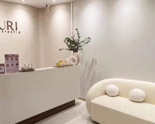 URI Spa & Massage Asok 分店寬敞明亮的接待區，配有簡潔的弧形櫃檯和舒適梳化，迎接客人體驗頂級水療和按摩服務。