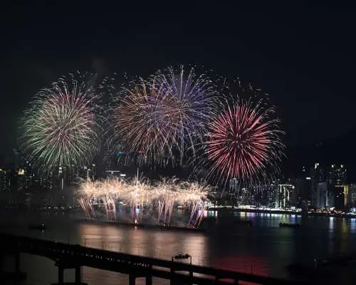 廣安大橋上方，2025釜山煙火節呈現大規模藍色、紫色與綠色煙火，照亮整個海灣與城市輪廓。