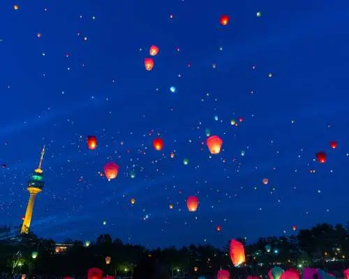 Countless red sky lanterns illuminating the night sky above Daegu, with the iconic E-WORLD Daegu Tower glowing in the background, creating a magical festival atmosphere.