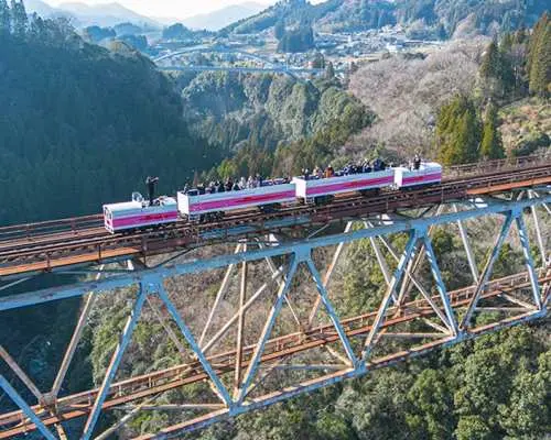 The Takachiho Amaterasu Railway Grand Super Cart train crosses a 105m high bridge, offering aerial views of lush valleys, a thrilling tour from Fukuoka.