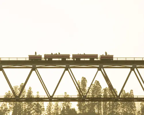 A silhouette of the Takachiho sky train crossing a towering bridge, carrying passengers to enjoy expansive views from high above, a unique Amaterasu Railway experience.