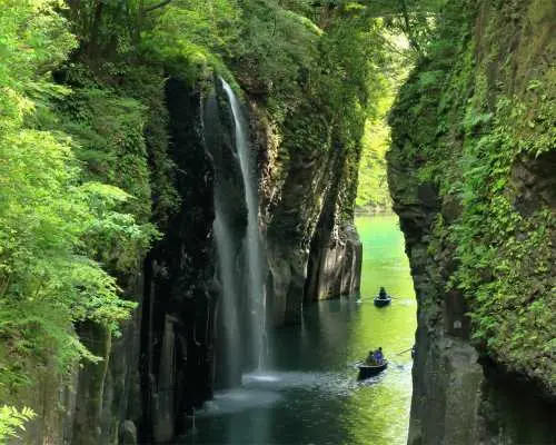 Thác nước hùng vĩ đổ xuống lòng Thung lũng Takachiho, hai chiếc thuyền nhỏ lướt nhẹ trên mặt nước xanh ngọc bích, hai bên là những vách đá hẻm núi xanh tươi.