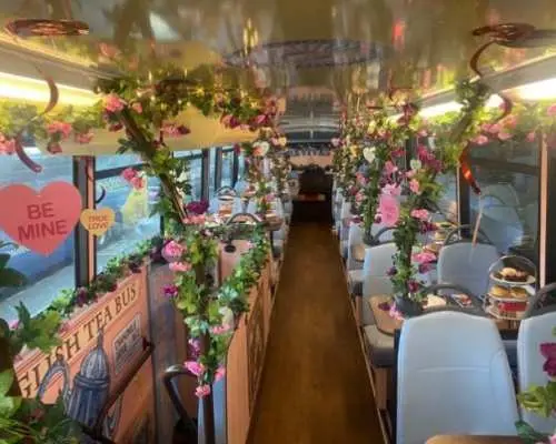 Romantic interior of the London Taylor Swift themed double-decker bus for afternoon tea, adorned with pink floral garlands and heart decorations, offering a festive dining atmosphere.