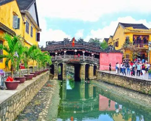 ホイアン旧市街の穏やかな運河にかかる象徴的な日本橋。鮮やかな黄色の伝統的な建物に囲まれ、ダナン・ホイアン観光ツアーの賑やかな名所です。
