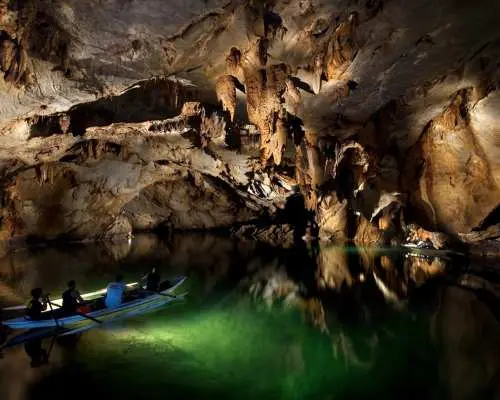 นักท่องเที่ยวพายเรือภายในถ้ำแม่น้ำใต้ดินปูเอร์โตปรินเซซา ปาลาวัน ชื่นชมหินงอกหินย้อยอันงดงามที่สะท้อนบนผิวน้ำ