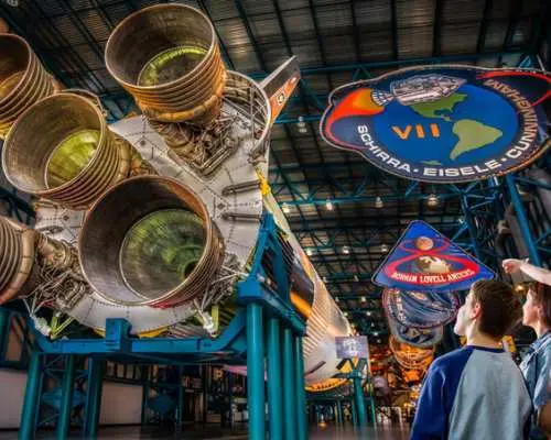 Visitors admiring the colossal Saturn V rocket display at Kennedy Space Center Visitor Complex, experiencing iconic space exploration history with the Orlando All-Inclusive Pass.