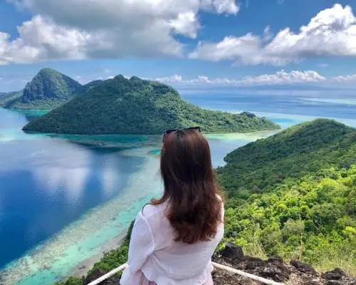 A visitor enjoying the panoramic island view of Tun Sakaran Marine Park from Bohey Dulang's peak, experiencing Semporna's natural charm for island hopping, hiking, and snorkeling.