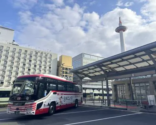 京阪觀光巴士停靠於京都站附近，背景可見京都塔，是京都秋葉一日遊的集合地點與出發交通工具。