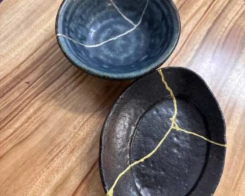 於沖繩金繼體驗中修復，展現金色線條美感的藍色碗和黑色碟。裂紋成為設計一部分，煥發新魅力。