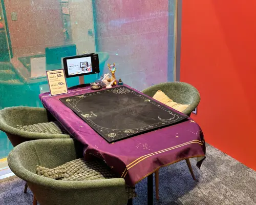 Modern fortune-telling consultation space in Seoul, featuring a purple tablecloth with a Tarot or Saju reading mat and two comfortable green chairs ready for customers.