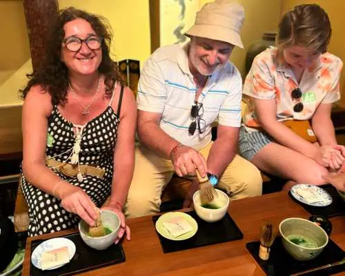Tourists engaged in a hands-on Uji matcha experience, carefully whisking traditional matcha, immersing themselves in Japanese tea ceremony culture and authentic flavors.