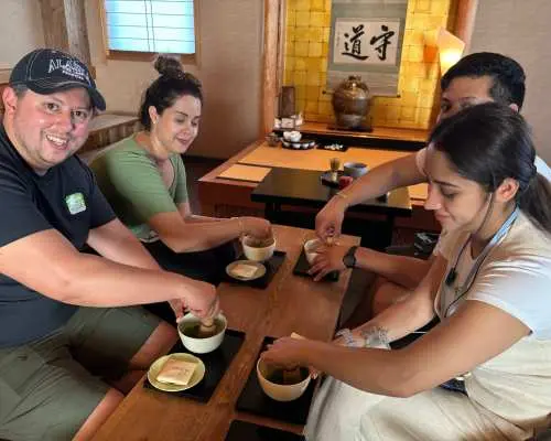 A group of friends excitedly learning and making traditional matcha during an Uji matcha experience, enjoying hands-on fun and authentic Japanese tea ceremony culture.