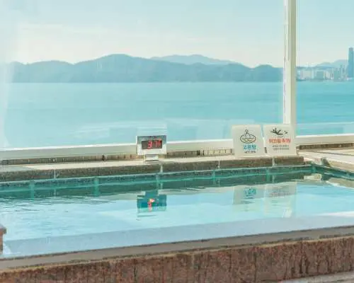 Busan Haeundae HILL SPA's outdoor hot spring bath, with shimmering water, offers stunning views of Busan Haeundae's seascape and cityscape outside the window, ensuring a comfortable relaxing experience.