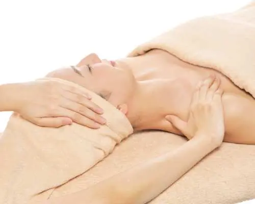 A skilled aesthetician performs a neck and shoulder massage as part of a high-quality anti-aging treatment at a Ginza, Tokyo salon, promoting face tightening and deep relaxation.