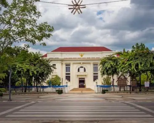 清邁古城區的三王紀念碑白色殖民風格建築，從人行道斑馬線對面遠眺，在多雲的天空下顯得典雅莊重。