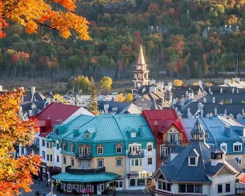 Mont-Tremblant Village in Eastern Canada (Montreal region), with colorful French-style buildings surrounded by vibrant autumn foliage, resembling a fairytale world, a 'Little Banff' photo spot.