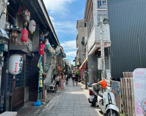 台南神農街の趣のある路地。両側には日本式の提灯と木造建築が立ち並び、観光客が行き交い、濃厚な歴史の趣を感じています。チャーター観光で手軽に訪れることができる文化的なスポットです。