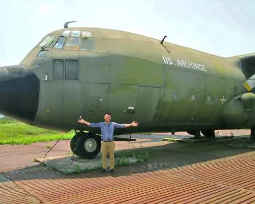 保存されたアメリカ空軍C-130軍用輸送機の前でポーズをとる訪問者。DMZツアー中に、戦時のアメリカ軍基地の歴史と具体的なつながりを提供します。