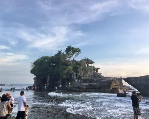 バリ島タナロット寺院の夕暮れ時。多くの観光客が夕日と海に浮かぶ寺院の幻想的な景色を鑑賞している様子。