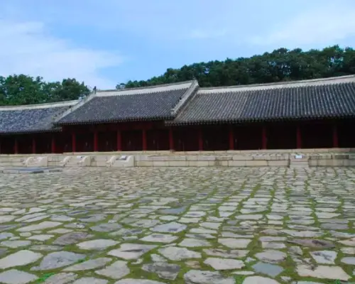 ソウル市内の世界遺産宗廟。青空の下、長い伝統建築と特徴的な石畳の広場が広がり、歴史探訪に最適な場所。半日ツアーで訪れ、その厳かな雰囲気を体験します。