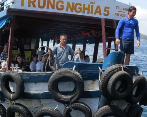 전통적인 'TRUNG NGHIA 5' 보트를 탄 승객들이 나트랑 3개 섬 스노클링 투어 중 섬들 사이의 아름다운 경치를 감상하며 이동하고 있습니다.