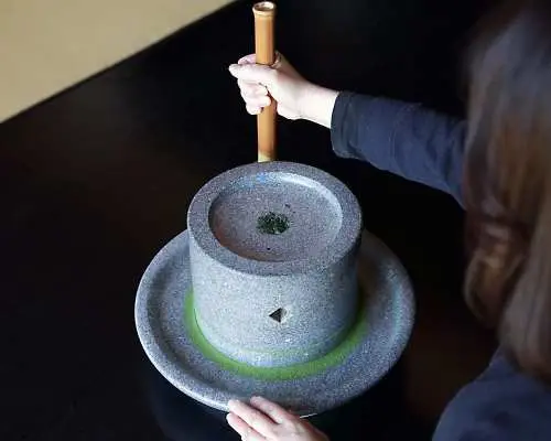 遊客親手操作傳統石磨，體驗八女茶葉研磨成精緻抹茶粉的過程，感受深厚的日本茶道文化。