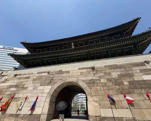 南大門市場に隣接する歴史的な国宝、崇礼門（南大門）の壮大な姿。青空の下、伝統的な韓国建築がソウルの歴史を物語る。