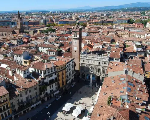 Aerial view of Verona's Piazza delle Erbe, featuring the towering Lamberti Tower and surrounding historic buildings, offering cultural exploration with the Verona Card.