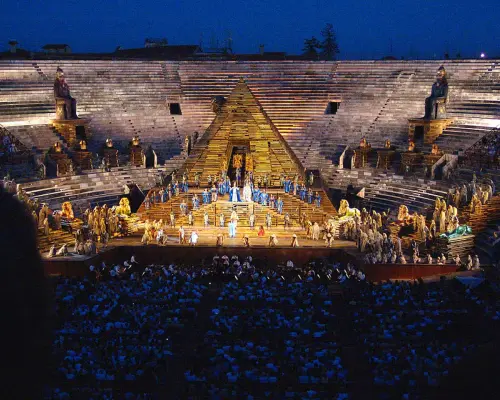Opera performance in full swing inside the Verona Arena, featuring an elaborate stage setup and a full audience in the circular stands, offering a rich cultural experience.
