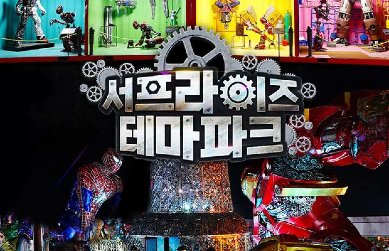 한국 제주 서프라이즈 테마파크 야경 입구. 거대한 로고와 톱니바퀴 장식, 배경에는 재활용 폐기물로 만든 영화 캐릭터 작품들이 전시되어 독특한 친환경 예술을 보여줍니다.