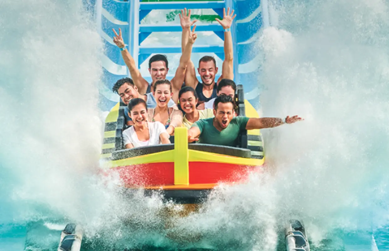 Thrilled visitors enjoying a thrilling water coaster ride at Desaru Coast Adventure Waterpark, splashing through waves and raising their hands in excitement.