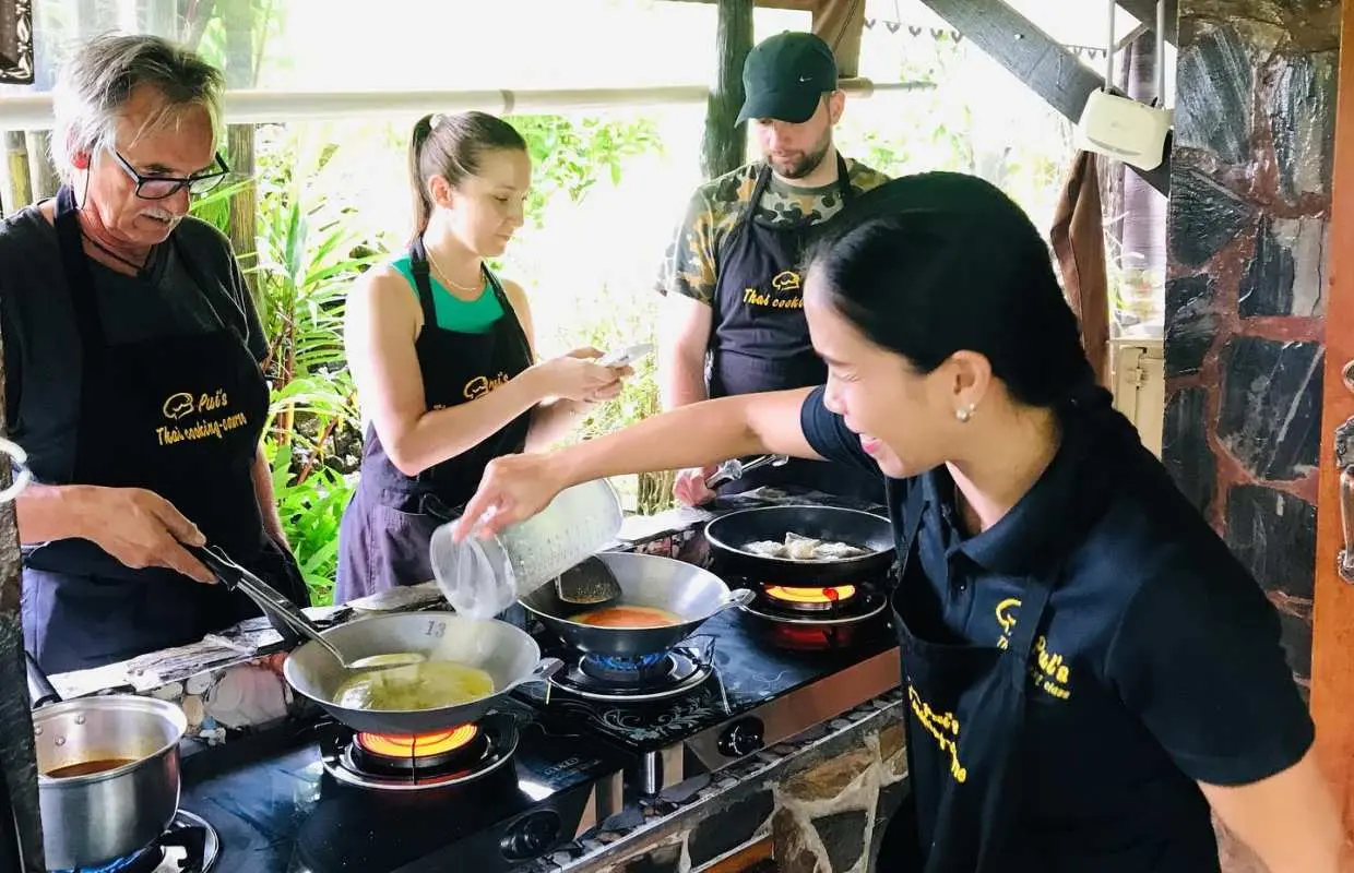 Khao Lak half-day cooking class participants learning to prepare authentic Thai dishes in a peaceful garden kitchen with a professional instructor.