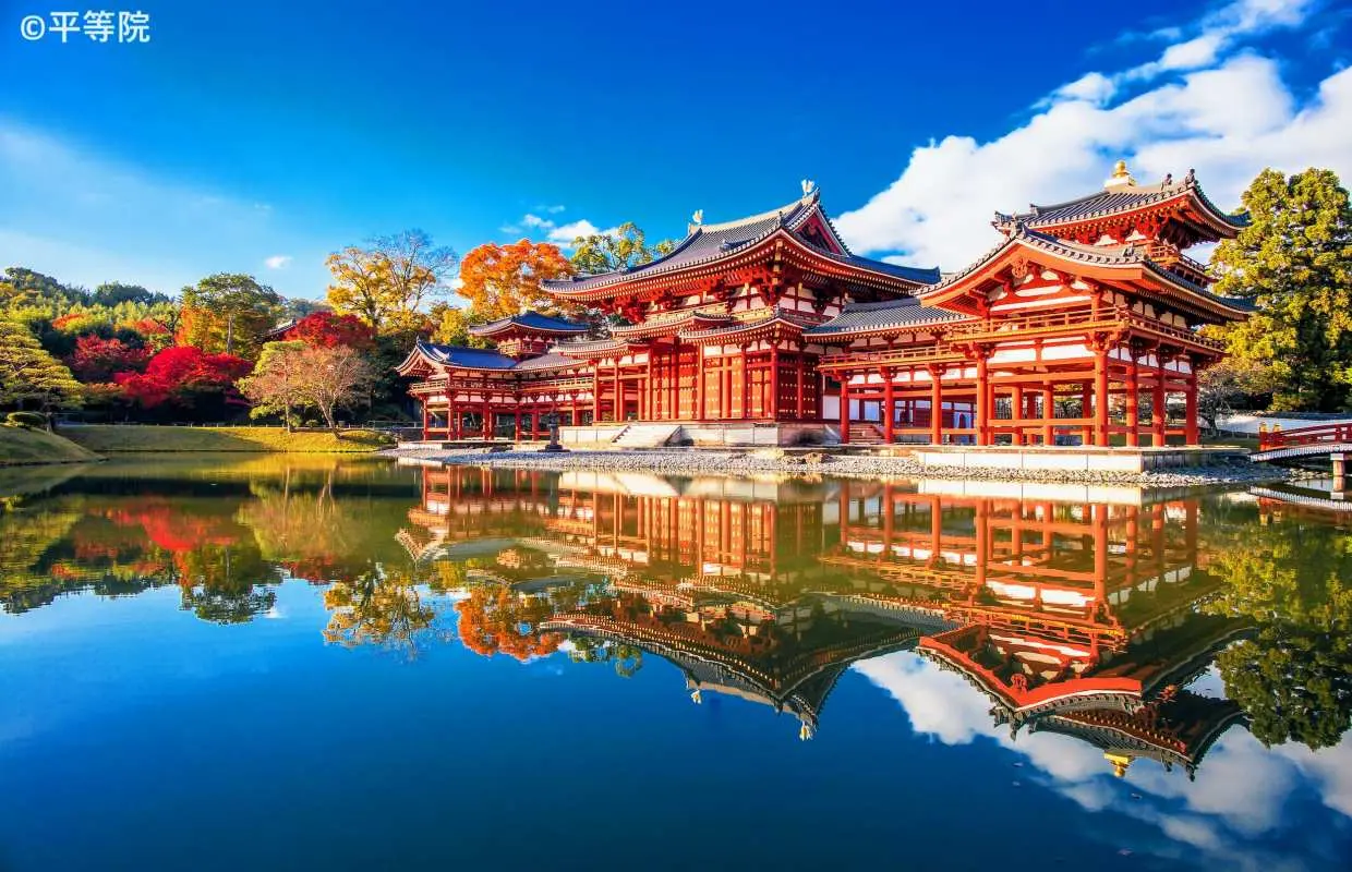 UNESCO World Heritage Byodoin Phoenix Hall in Uji, Kyoto, surrounded by vibrant autumn foliage, its magnificent architecture perfectly reflected in the serene pond.
