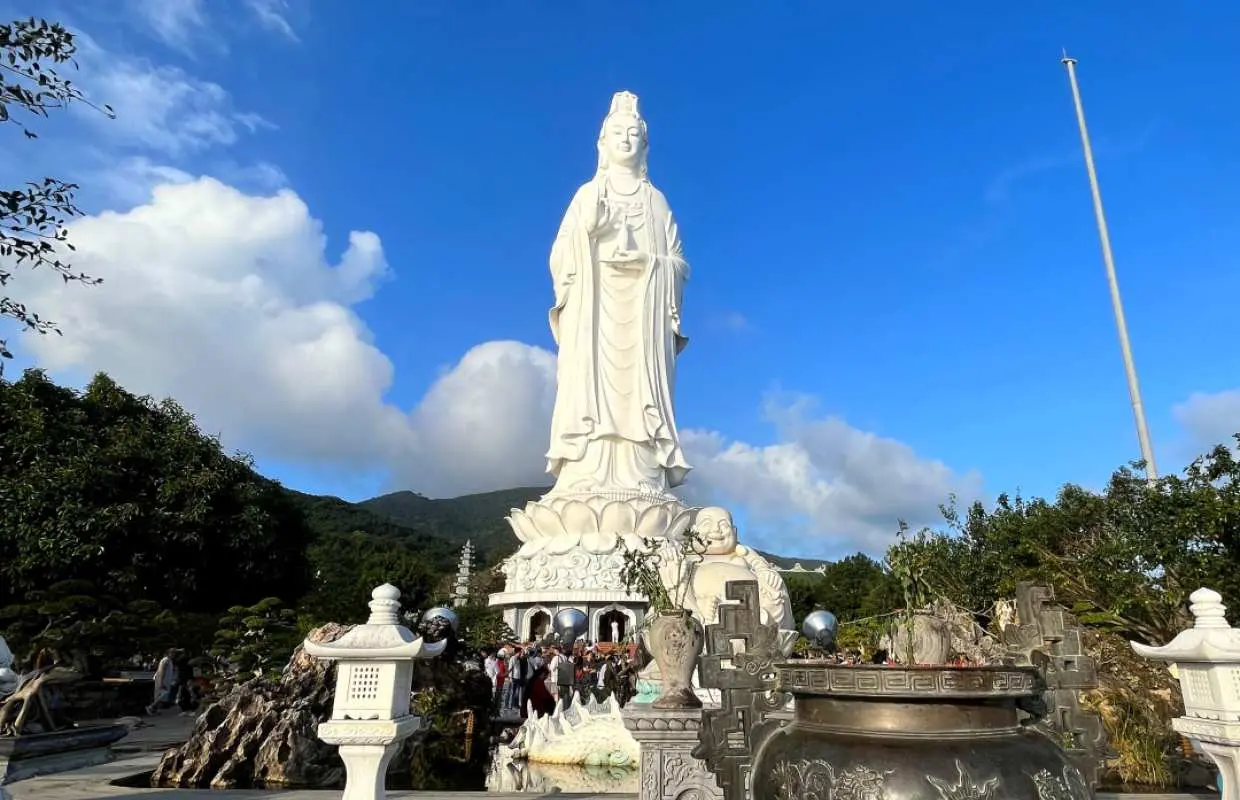 다낭 영흥사(린응사)의 웅장한 해수관음상, 청명한 하늘 아래 평화로운 분위기를 담은 호이안 버스 투어 명소.