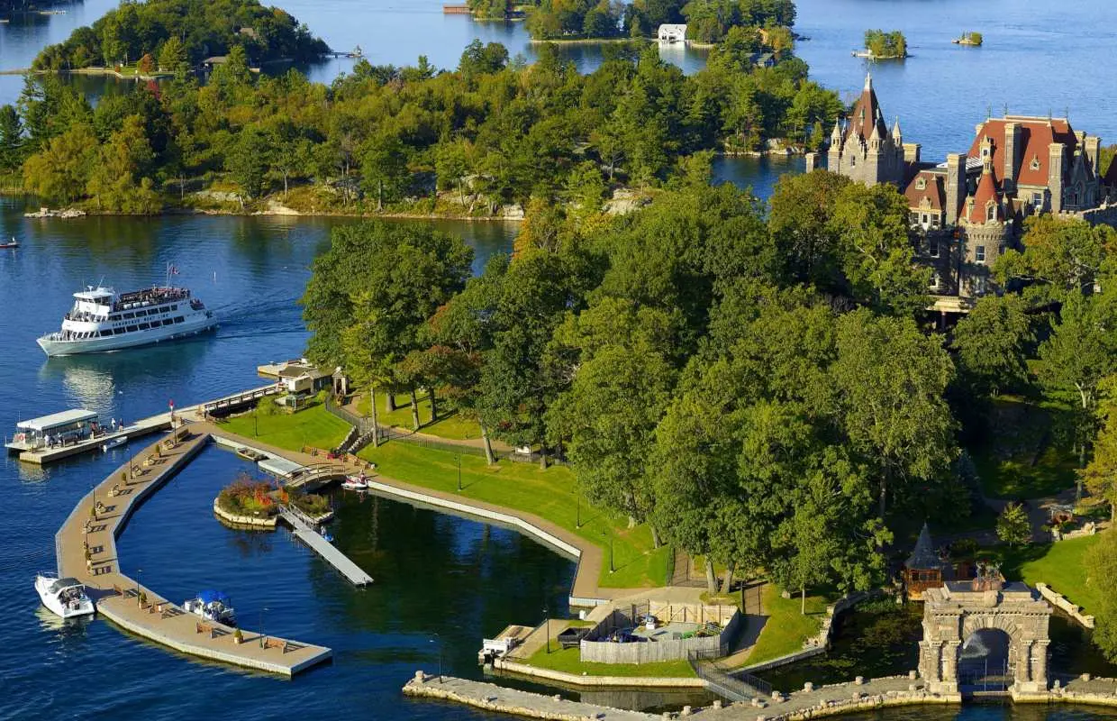 Boldt Castle in Canada's Thousand Islands, surrounded by lush green islands and deep blue waters, with a tour boat passing by, showcasing Eastern Canada's natural beauty and history.