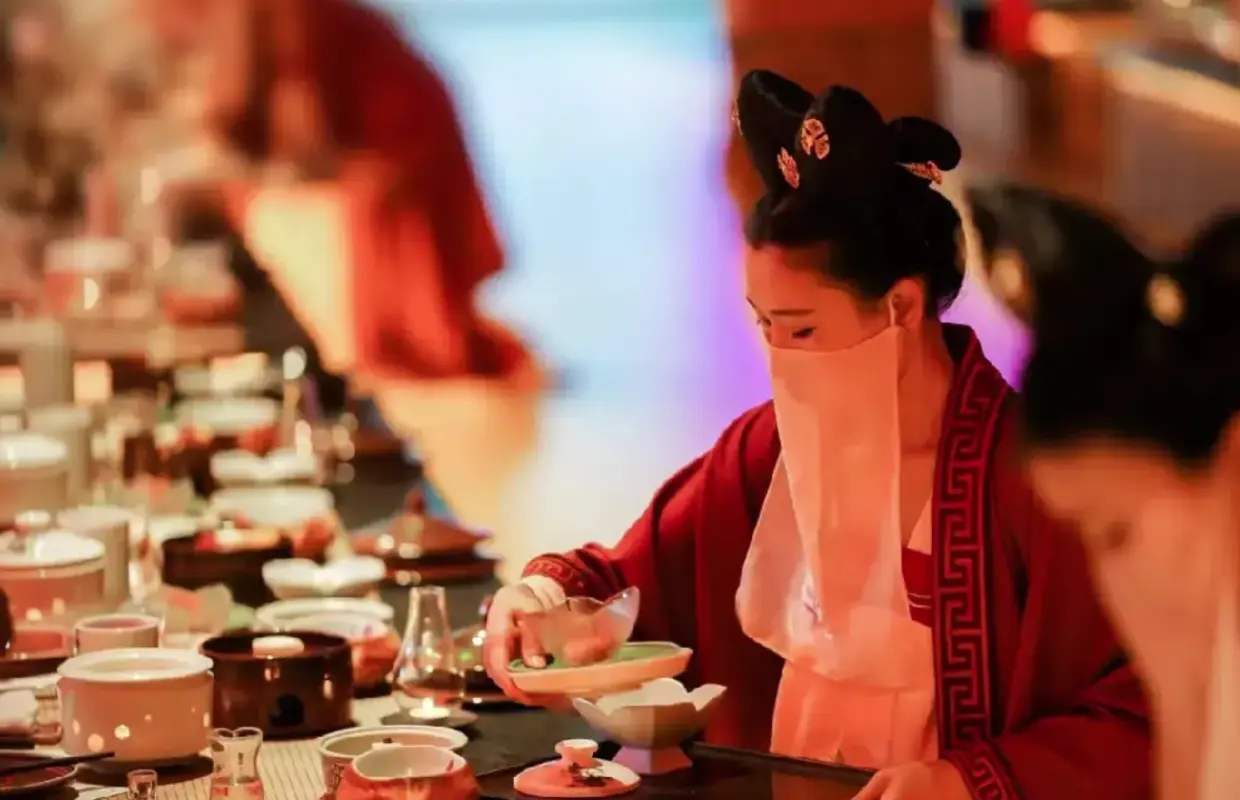 In Beijing Palace Banquet, a 'palace maid' in elegant Hanfu gracefully serves exquisite imperial dishes to guests, creating an immersive dining experience.